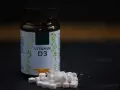 Flasche mit Vitamin D3 und Pillen. Wann einnehmen? Am besten mit einer Mahlzeit, um die Aufnahme zu verbessern.