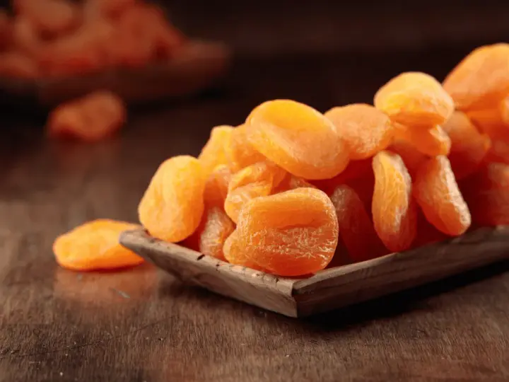 Getrocknete Aprikosen in einer Holzschale, ein gesunder Snack voller Vitamine.