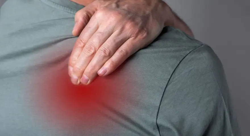 Mann greift sich an die Schulter, wo ein roter Fleck Schmerz und Entzündung bei BWS-Syndrom andeutet.