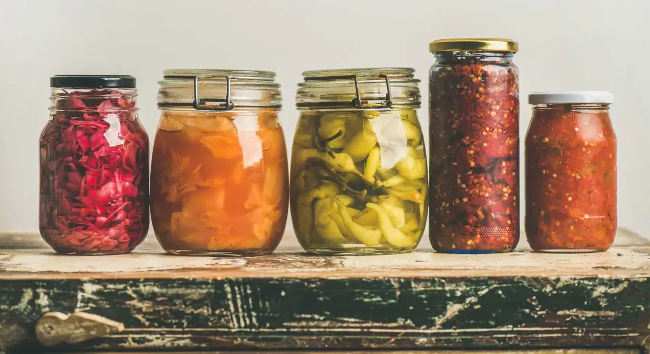 F&uuml;nf Gl&auml;ser mit fermentierten, probiotischen Lebensmitteln: Rotkohl, Sauerkraut, eingelegte gr&uuml;ne Chilis, scharfe Paste und Tomaten-Chutney.